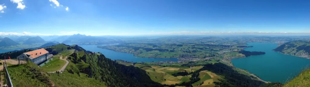 Panorama depuis un sommet montrant lacs, collines et vallée verdoyante.