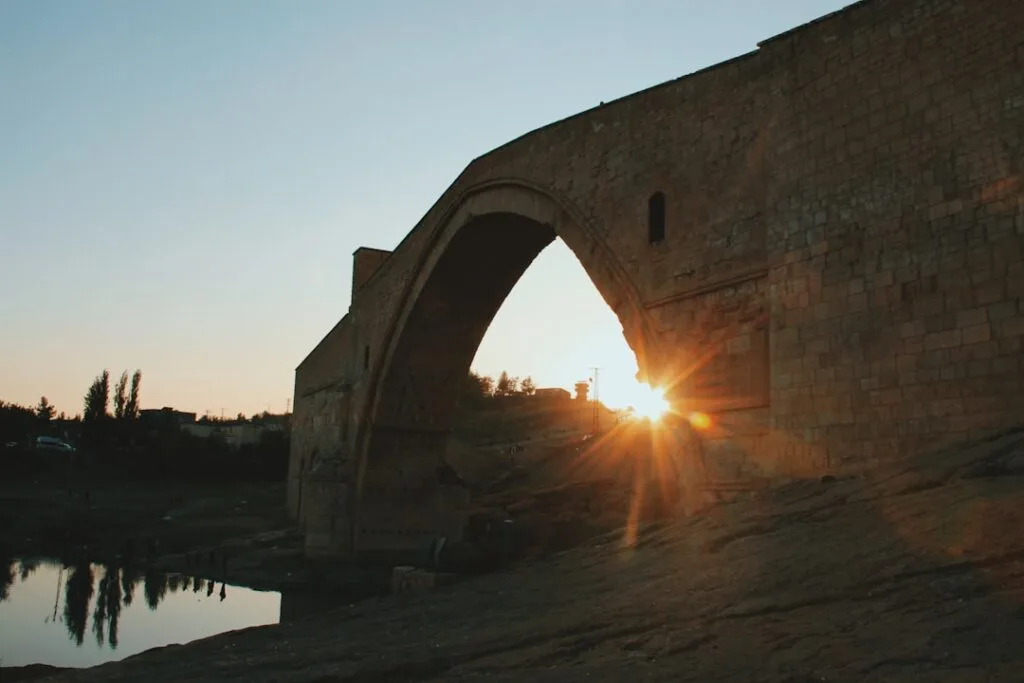 Pont en pierre en arc au coucher de soleil avec reflet