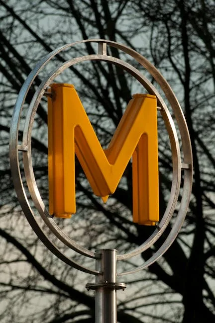 Grand M jaune du métro de Milan sur fond d'arbres.