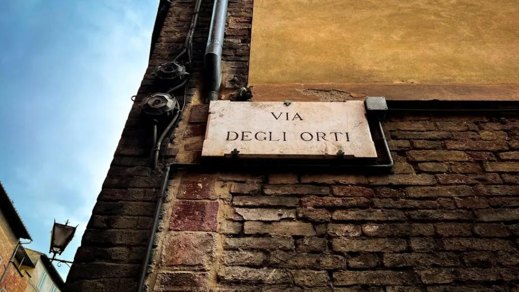 Plaque de rue « VIA DEGLI ORTI » fixée sur un mur en briques