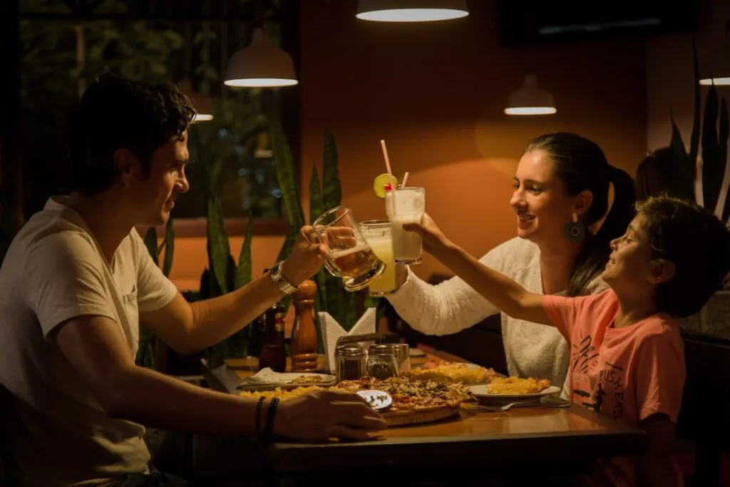 Famille levant leurs verres autour d'une pizza dans un restaurant convivial