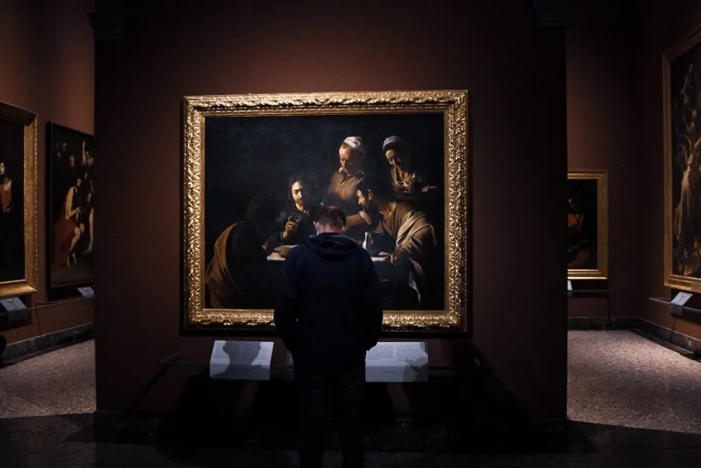 Visiteur contemplant un tableau baroque dans une salle du musée de Milan