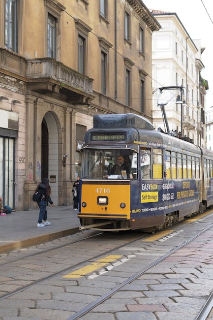 Tram giallo storico a Milano che percorre strada acciottolata centrale