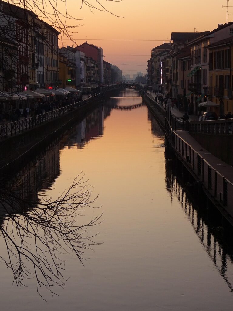 Tramonto arancione sui Navigli di Milano con riflessi sull'acqua calma