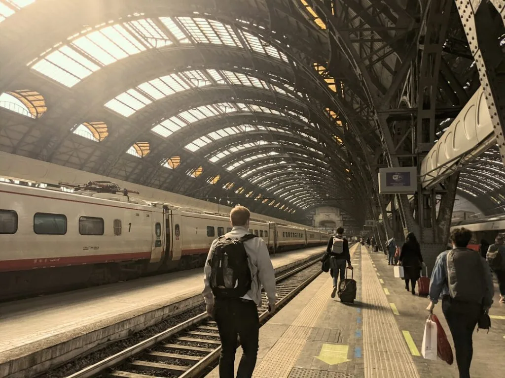 Voyageurs avec bagages sur quai sous la grande verrière de Milan