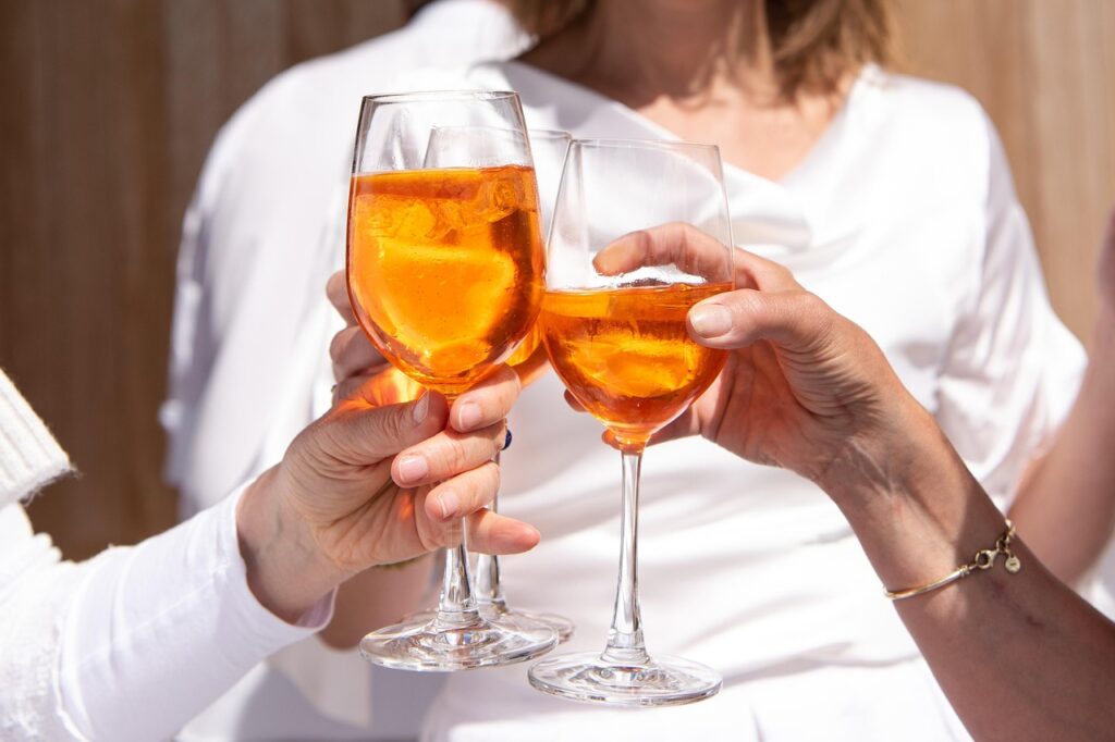 Gruppe von Freunden stößt mit Spritz-Gläsern auf einer Mailänder Terrasse an
