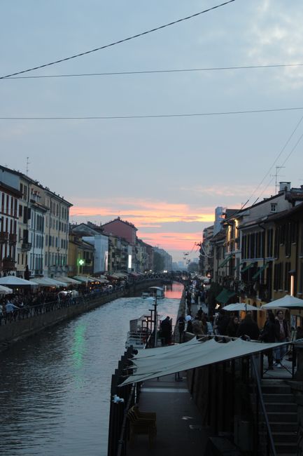 Abendlicher Naviglio-Kanal in Mailand mit beleuchteten Cafés und Menschenpromenade