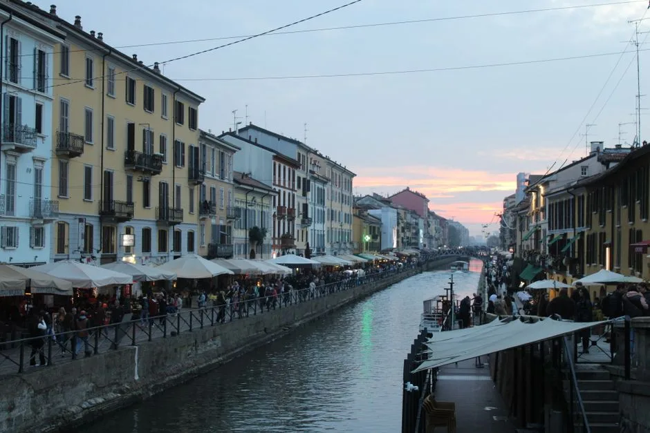 Vue sur le canal des Navigli à Milan, terrasses et passants au crépuscule