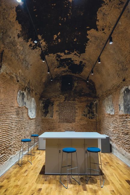 Historischer Gewölberaum mit Barhockern und modernem Tisch in Mailand