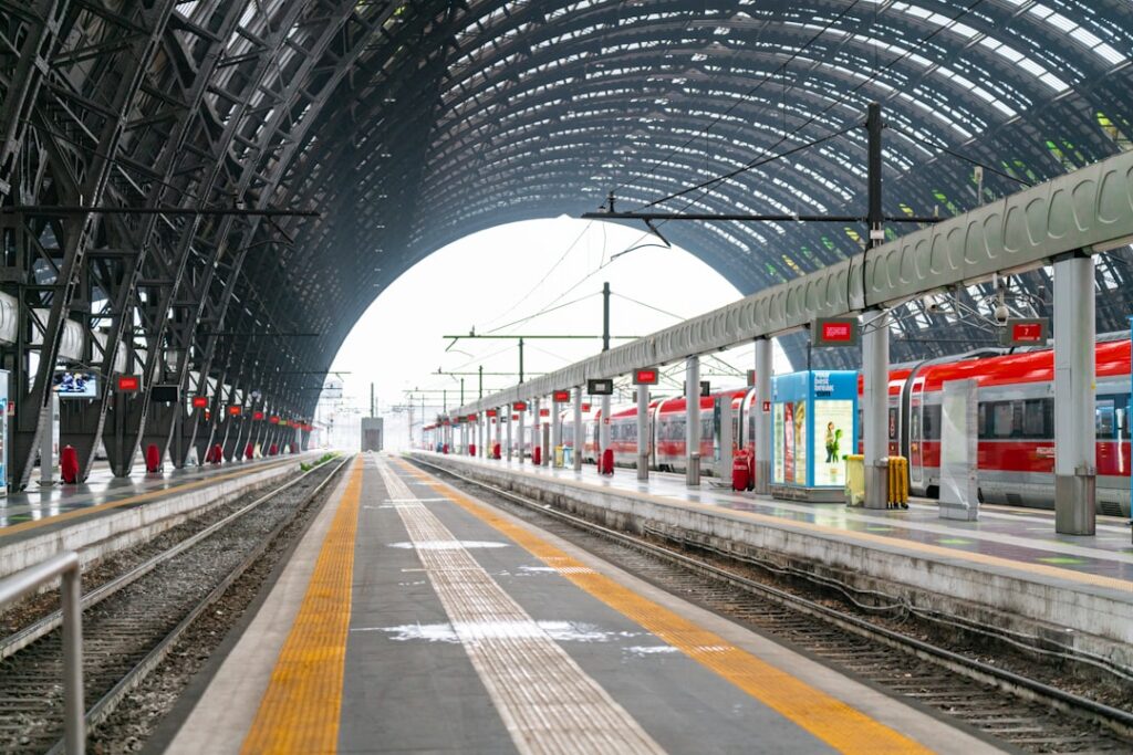 Langer Bahnsteig unter der gewölbten Halle im Mailänder Hauptbahnhof mit Zügen