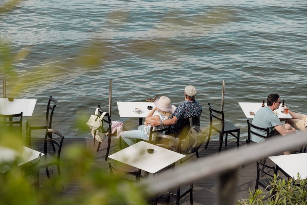 Terrazza di un ristorante sul lago con pesce alla griglia e persone che pranzano