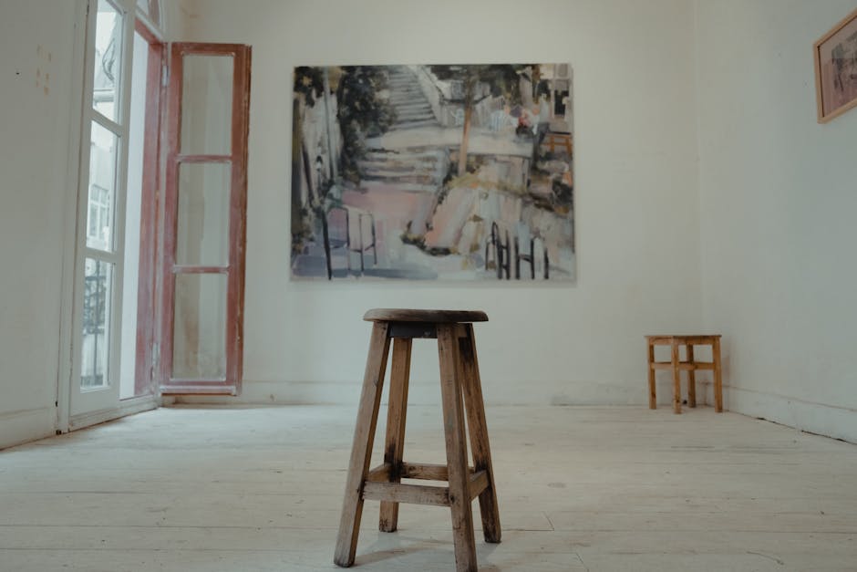 Interno di una piccola galleria d'arte con dipinti alle pareti e pavimento in legno