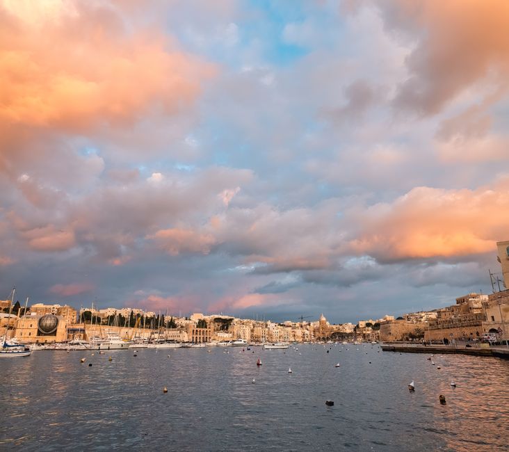 zonsondergang boven de Grand Harbour met etende gasten aan het waterfront in Valletta