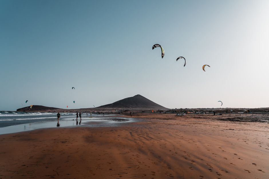 Kitesurfers en rode vliegers op het strand van El Médano