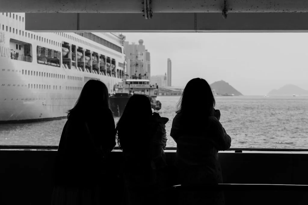 Silhouetted people watching cruise ship at Naples harbor from ferry window