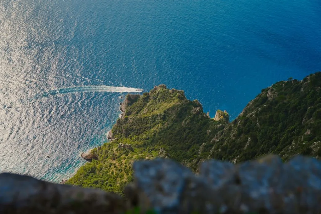 Speedboat slicing turquoise water beside rugged Capri cliffs near Naples