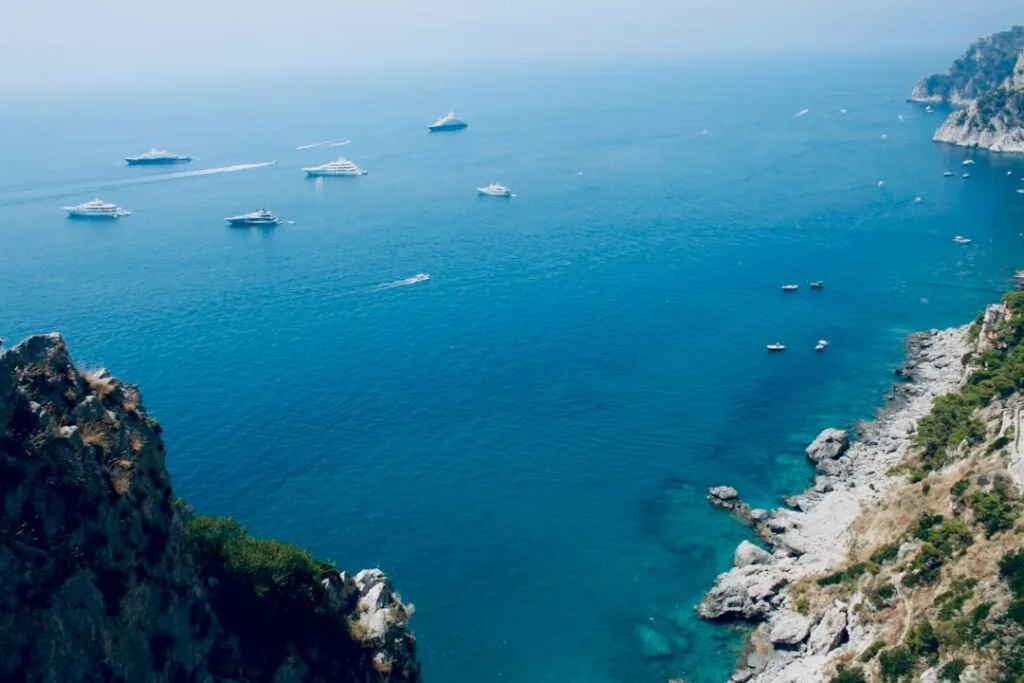 Several yachts scattered across deep blue waters off the Capri coast