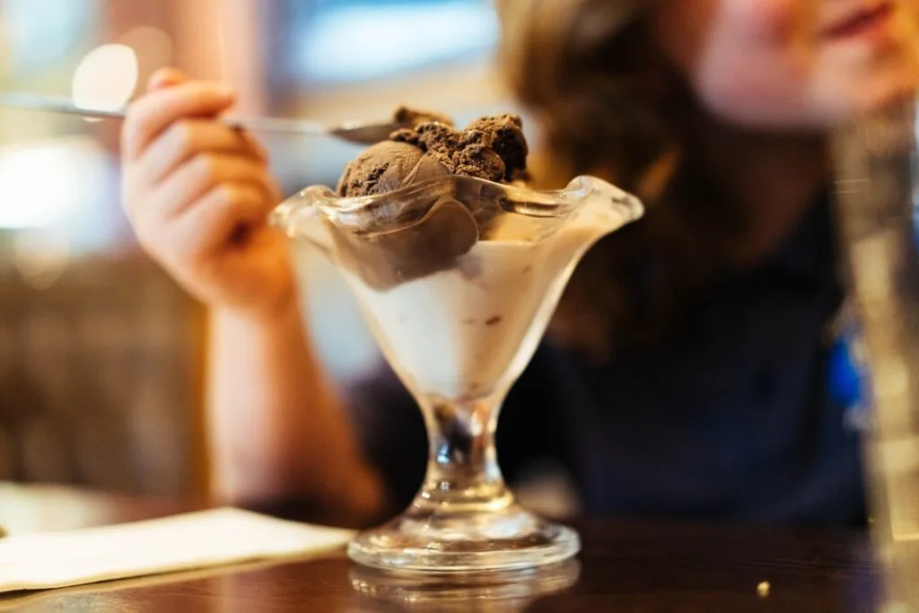 Close-up of a child tasting gelato with a small spoon