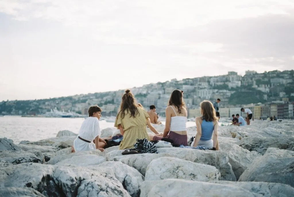 Group of friends sitting on rocks by the Naples waterfront