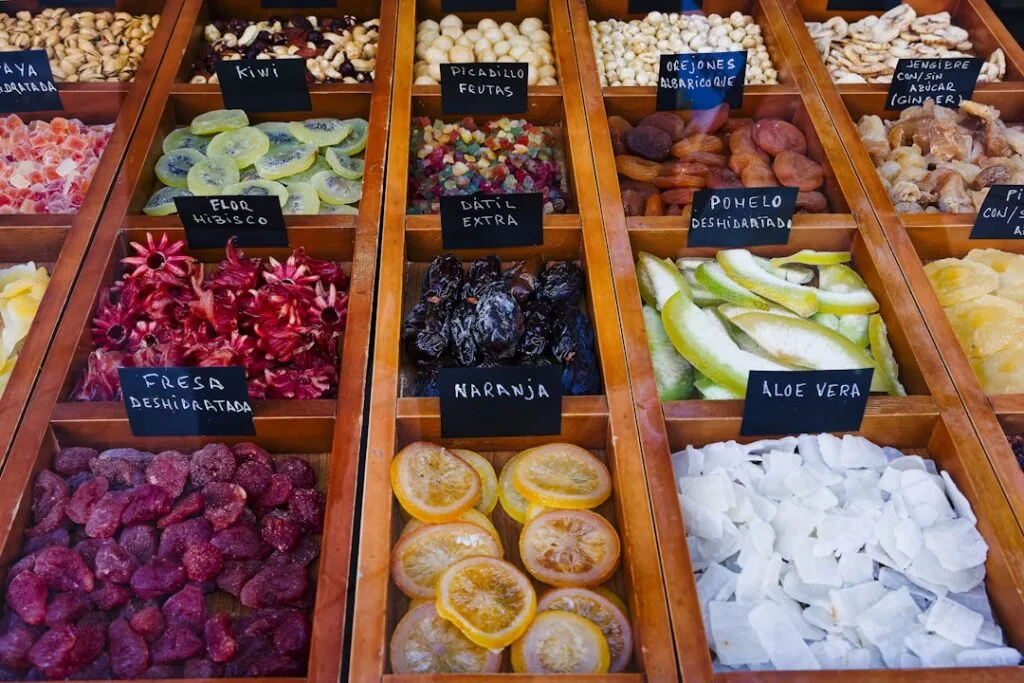 Rows of candied and dried fruits in wooden trays for toppings