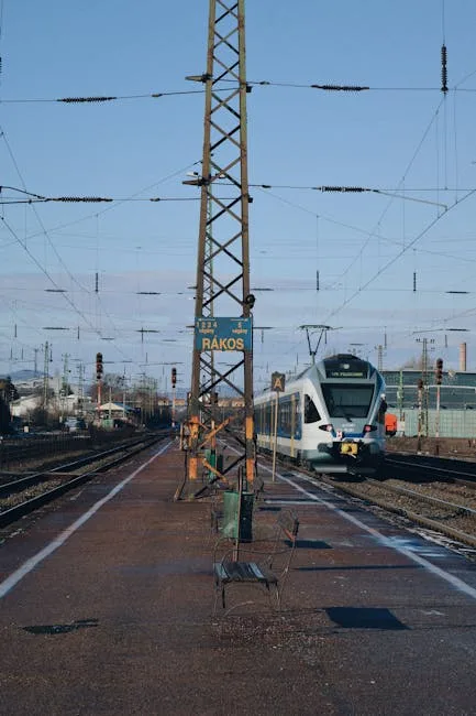 Commuter train at a platform with overhead wires and empty benches.