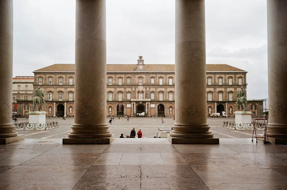 View through colonnade columns onto Piazza del Plebiscito and Royal Palace, Naples.
