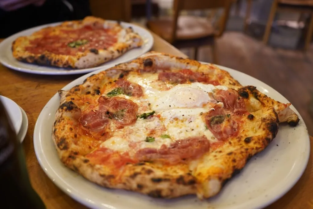 Two Neapolitan pizzas served on plates in Naples pizzeria