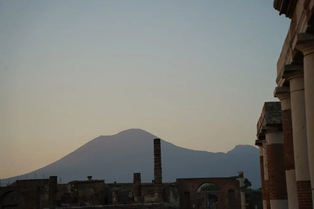 Mount Vesuvius silhouette rising behind Pompeii ruins at dusk