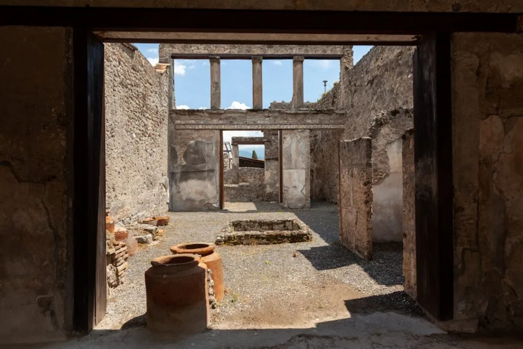 Sunlit Pompeii house courtyard with terracotta storage jars and open sky