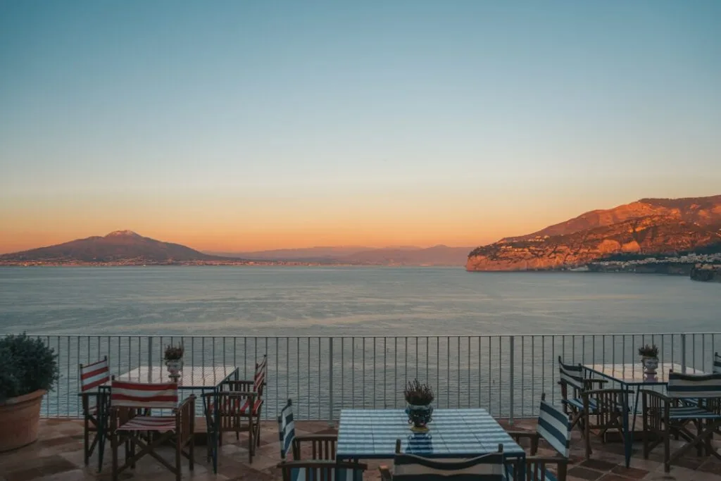 Terrace dining tables overlooking Gulf of Naples and Mount Vesuvius at sunset