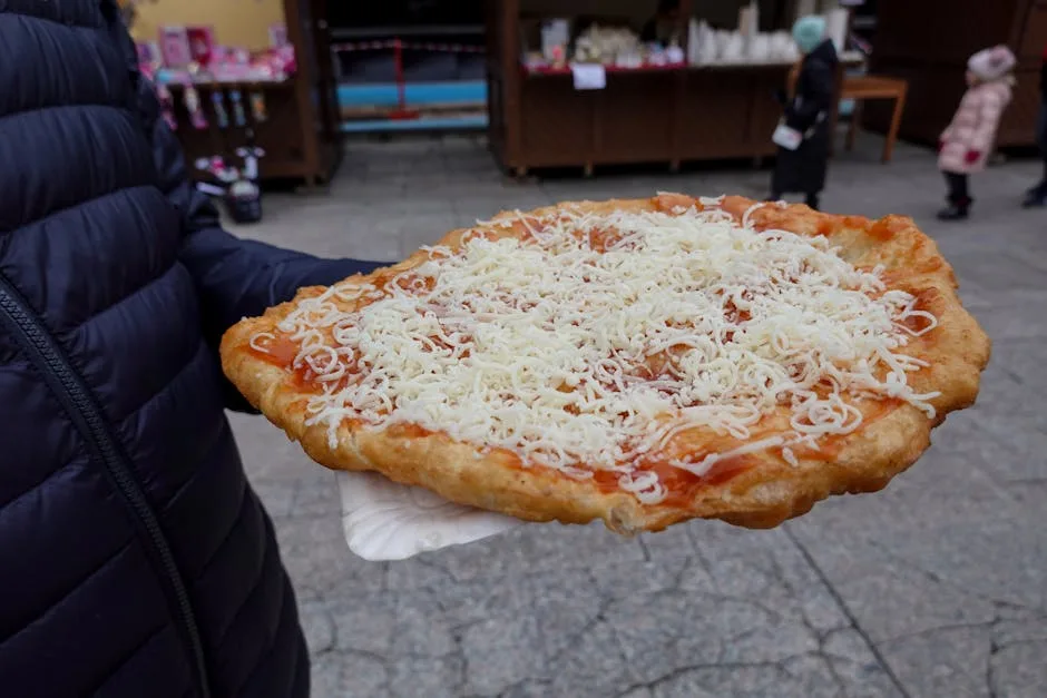 Street vendor holding large fried pizza topped with grated cheese in Naples