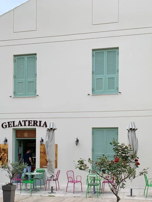 Pastel-shuttered gelateria with colorful chairs outside in Naples