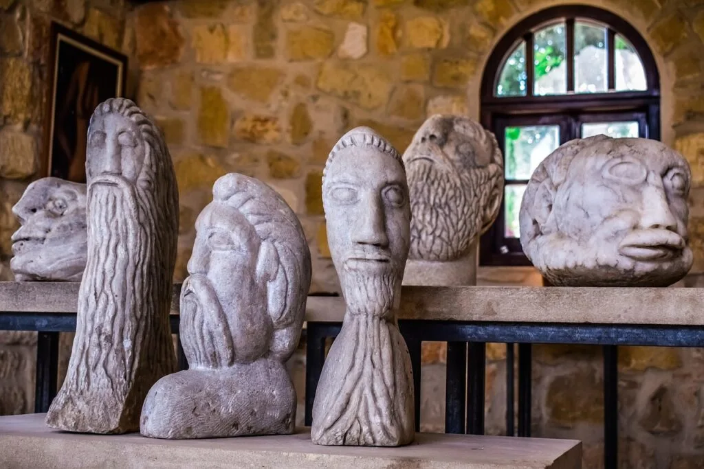Ancient carved stone heads lined on a shelf in Naples museum