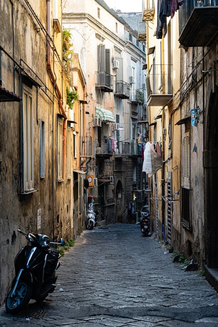 Narrow cobbled Naples alleyway with scooters, balconies, and hanging laundry