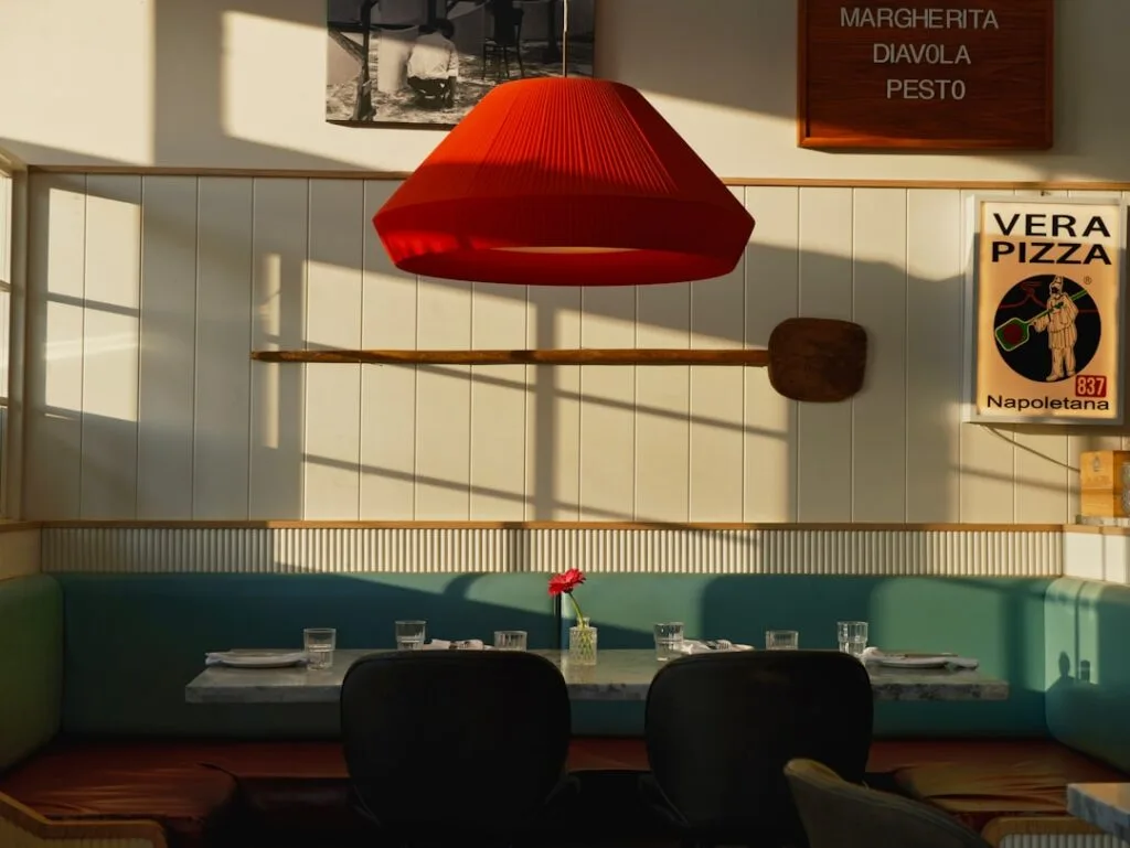 Cozy Naples pizzeria seating with red lamp, pizza peel and sign