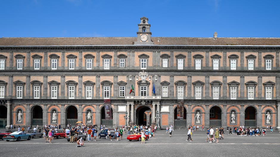 Royal Palace of Naples facade with tourists in the square.