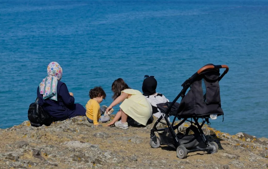 Familie sitzt am Meer auf Klippe mit Kinderwagen, Neapel-Küste