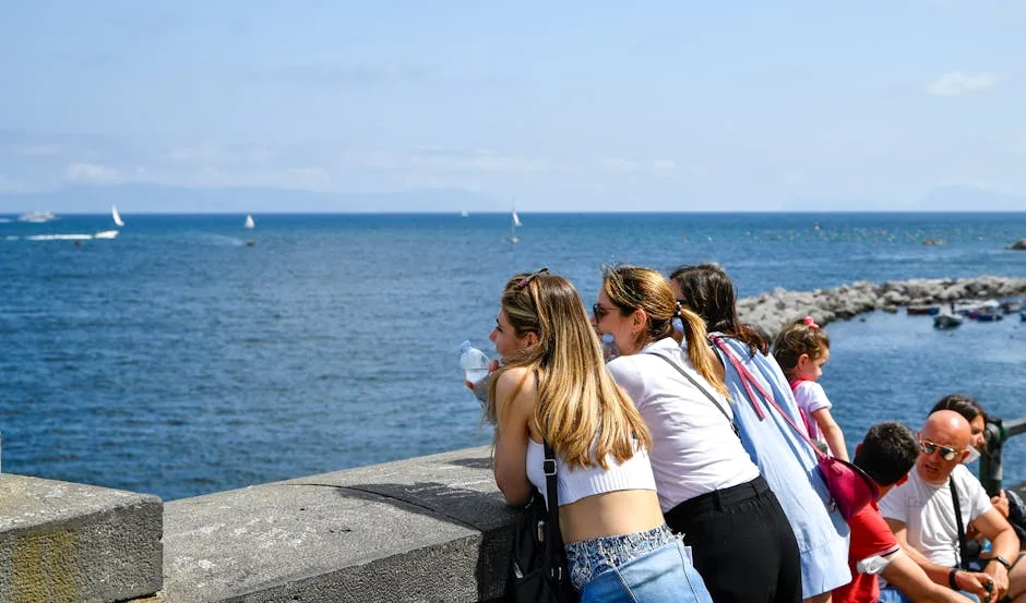 Touristen lehnen an Ufermauer und blicken aufs Meer bei Neapel.