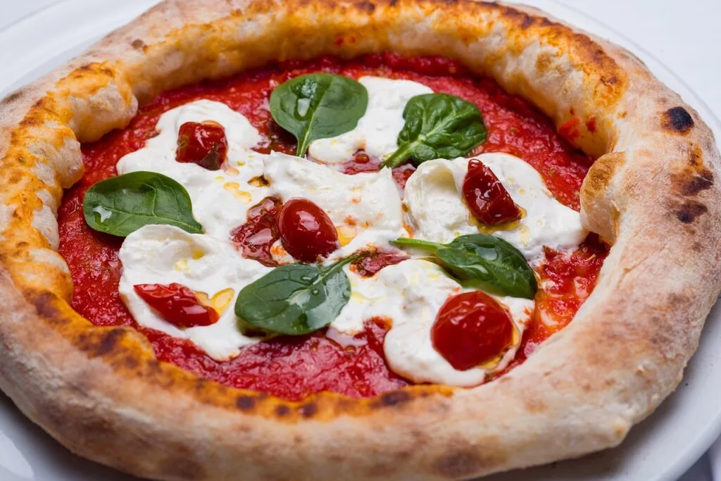 Neapolitanische Pizza mit Burrata, Tomatensauce und Spinatblättern in Neapel