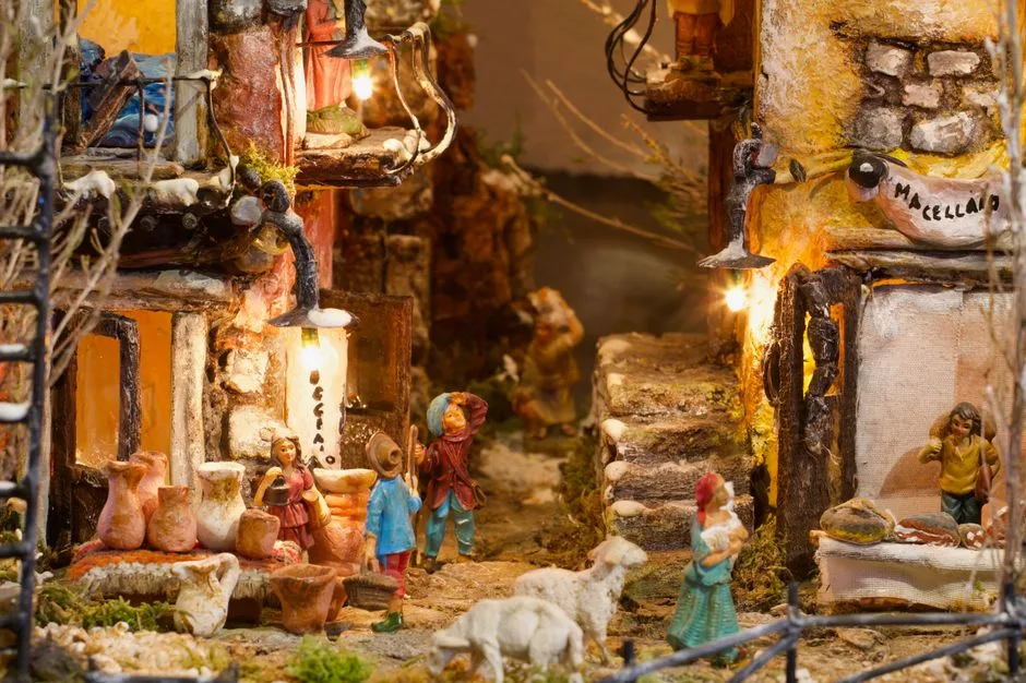 Neapolitanische Weihnachtskrippe mit kleinen Figuren, Marktständen und Beleuchtung.
