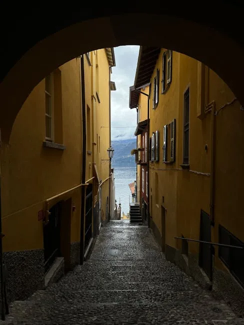 Gasse mit Bogen und Kopfsteinpflaster führt zum Wasser am Comer See.