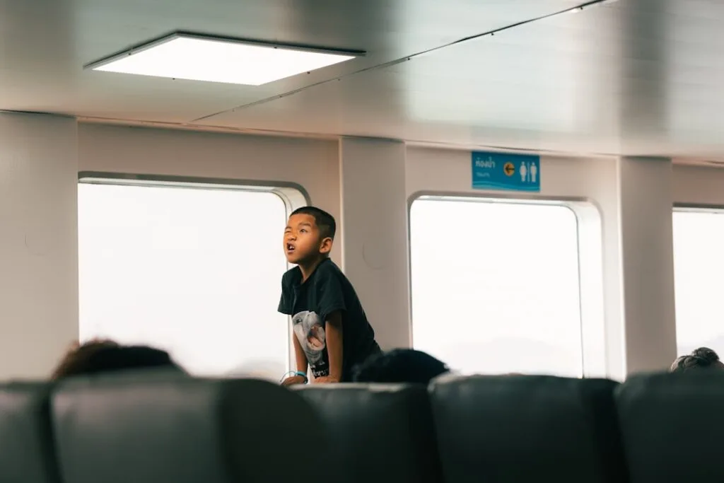 Child standing inside a Lake Como ferry, gazing out the window