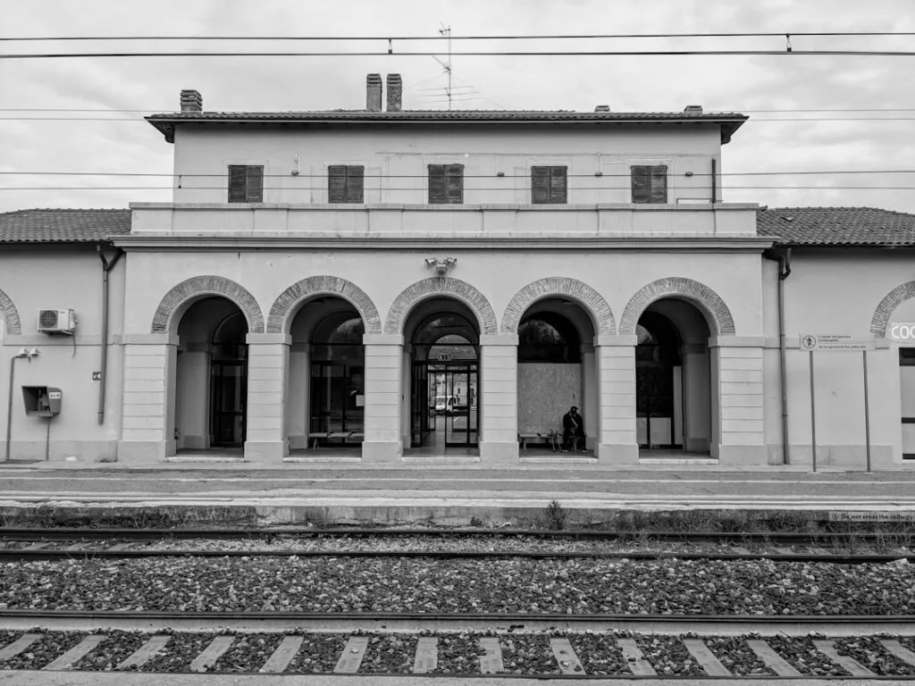 Small train station near Lake Como with arched portico and tracks