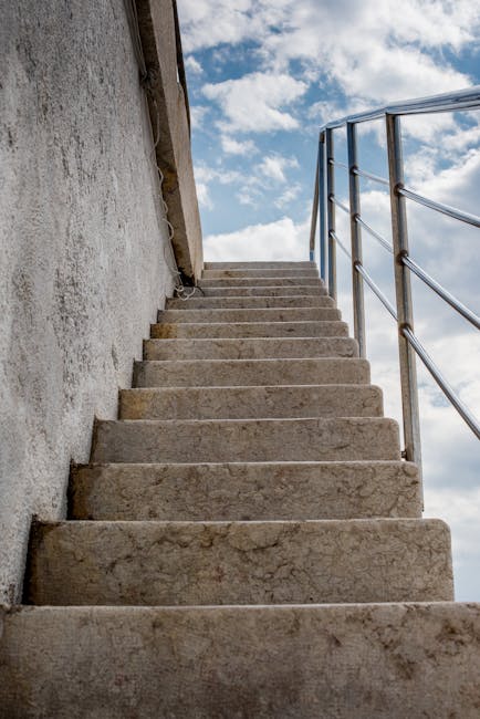 Wettergebleichte Steintreppe mit Edelstahlgeländer und Himmel darüber