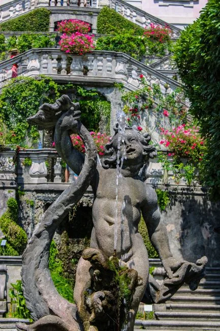 Statue de fontaine baroque devant balustrade fleurie d'une villa Lac come