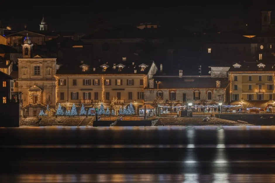 Promenade illuminée et sapins décorés reflétés sur l'eau de Lac come