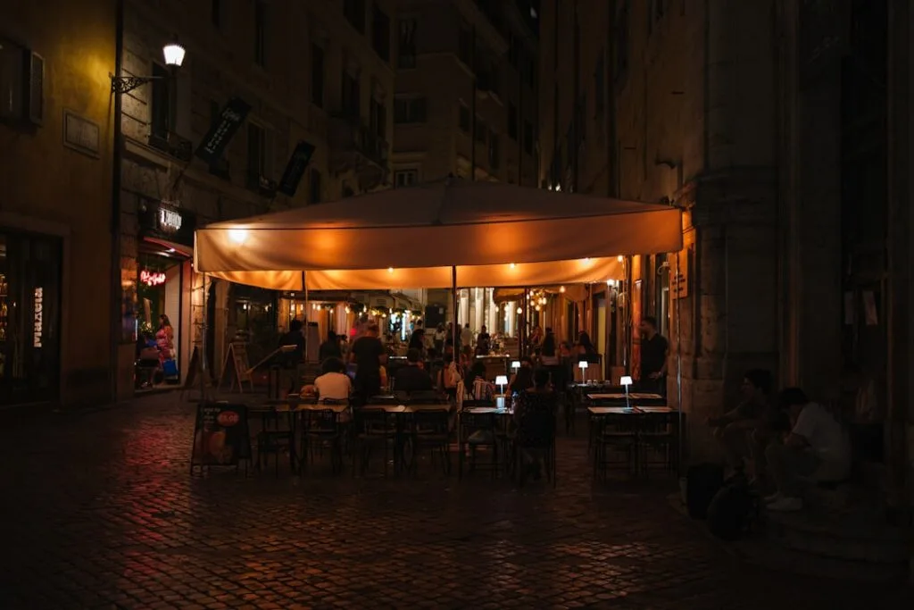 Terrasse éclairée d'un café sous chapiteau sur une ruelle pavée de Côme