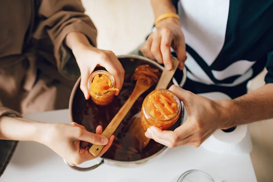 Deux personnes remplissant des bocaux de conserves maison avec spatule.