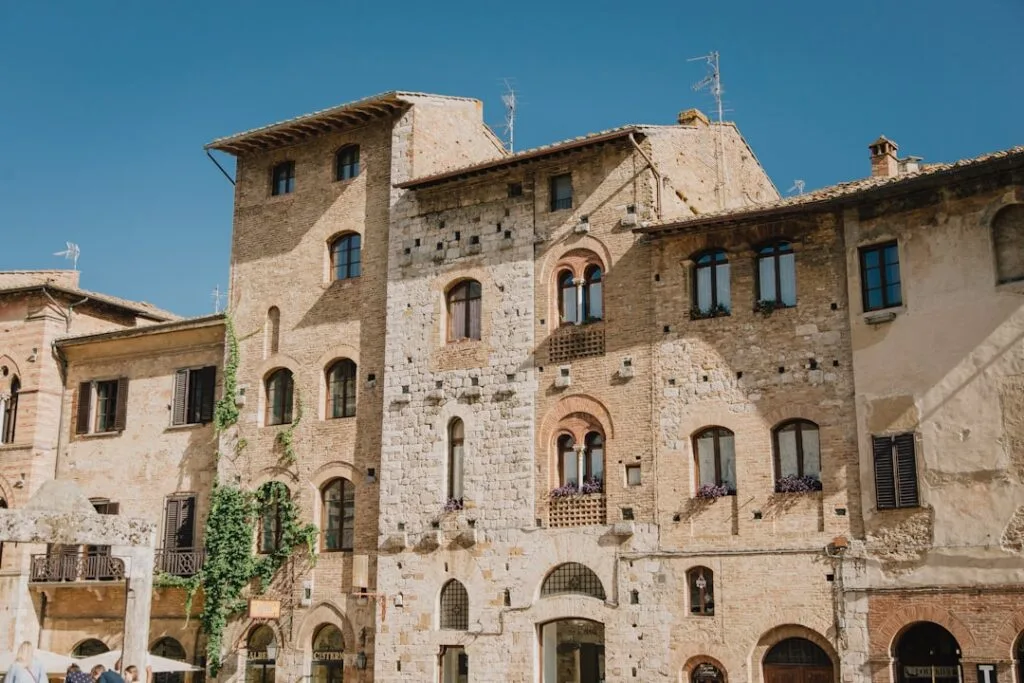 Façades en pierre médiévales et fenêtres fleuries à San Gimignano