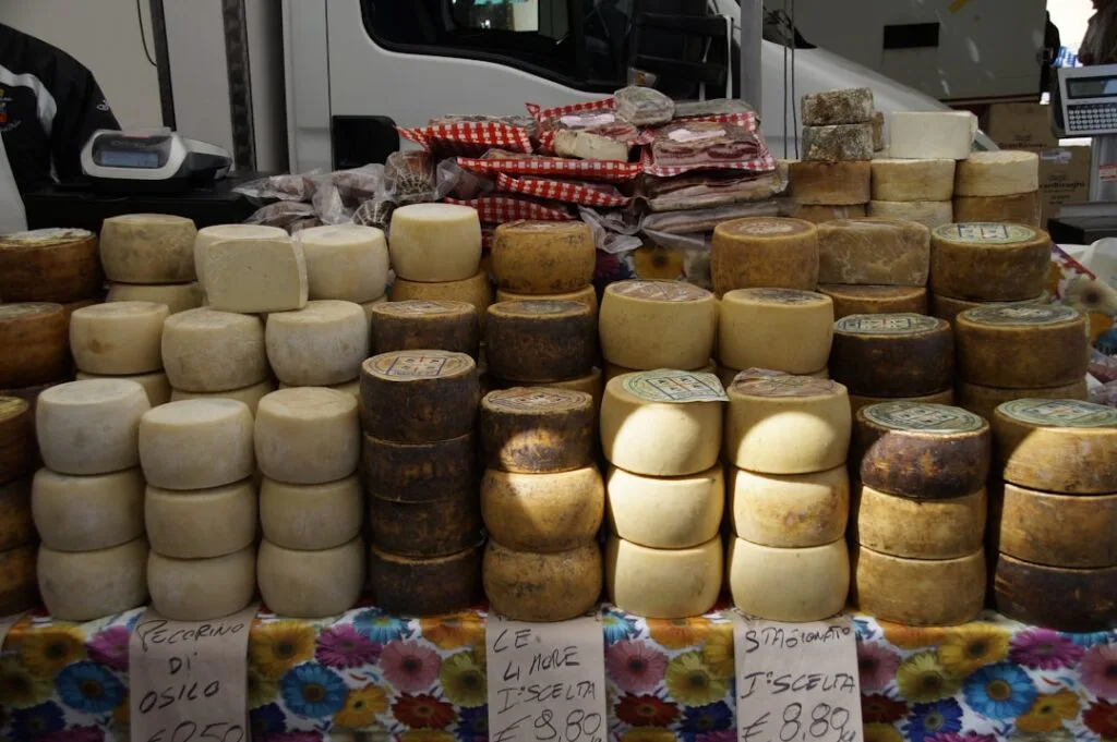 Rangées de fromages ronds empilés sur un étal de marché à San Gimignano